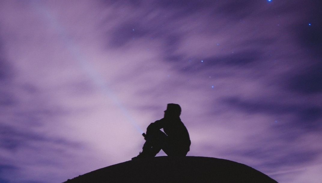 Te llame a soñar grande. Joven viendo al cielo en la oscuridad