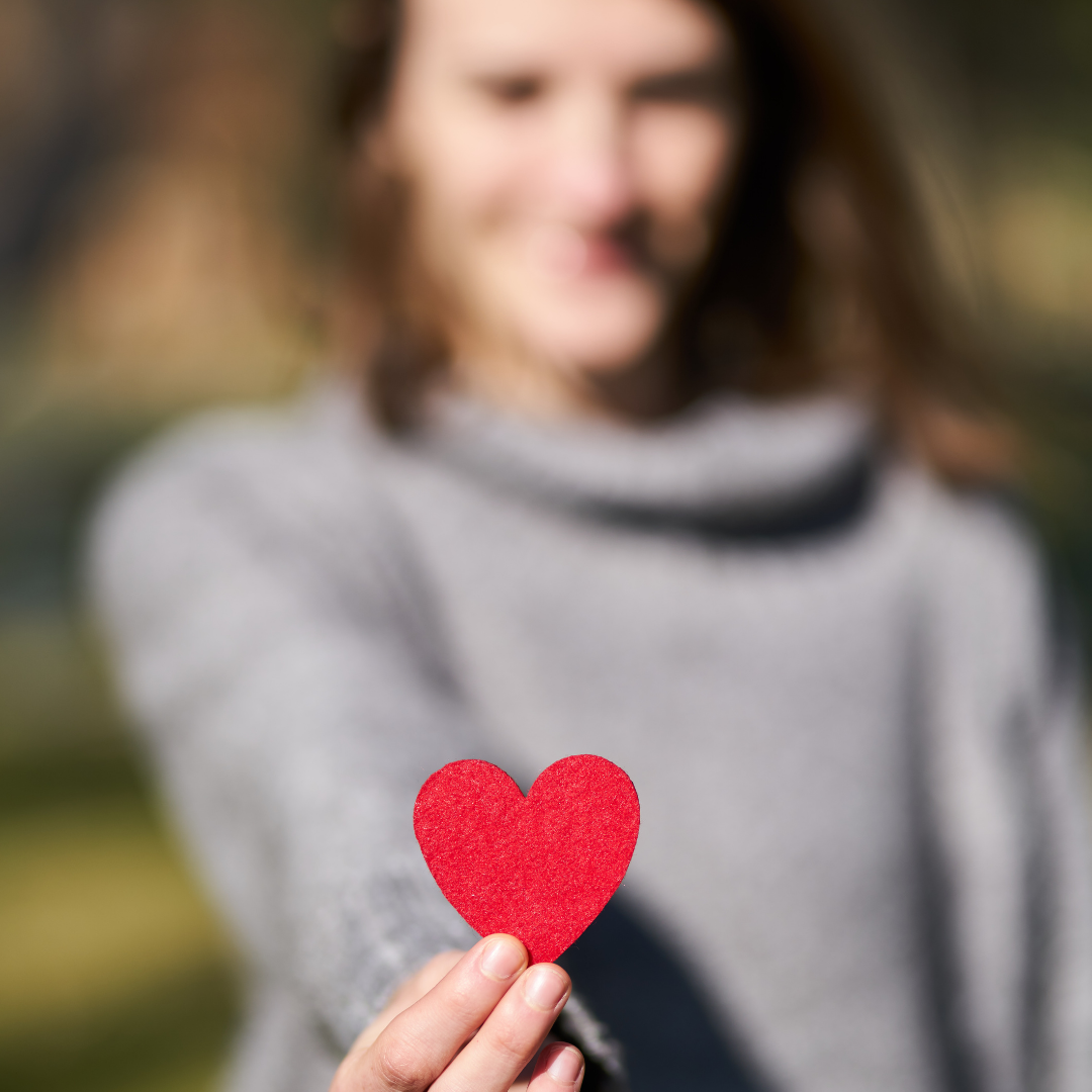 La castidad  El encuentro con el verdadero amor. Mujer de fondo mostrando un corazón de papel